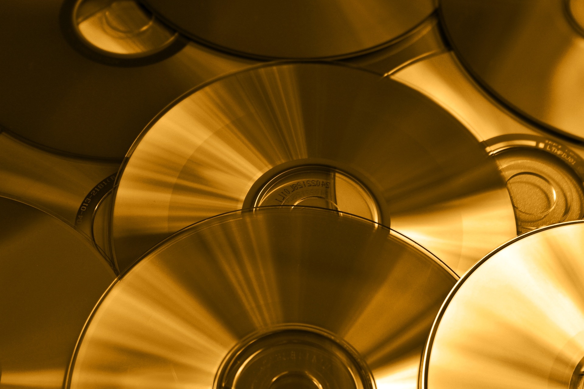 Das Foto zeigt viele golden-gelb-schwarz reflektierende CDs, die übereinander liegen